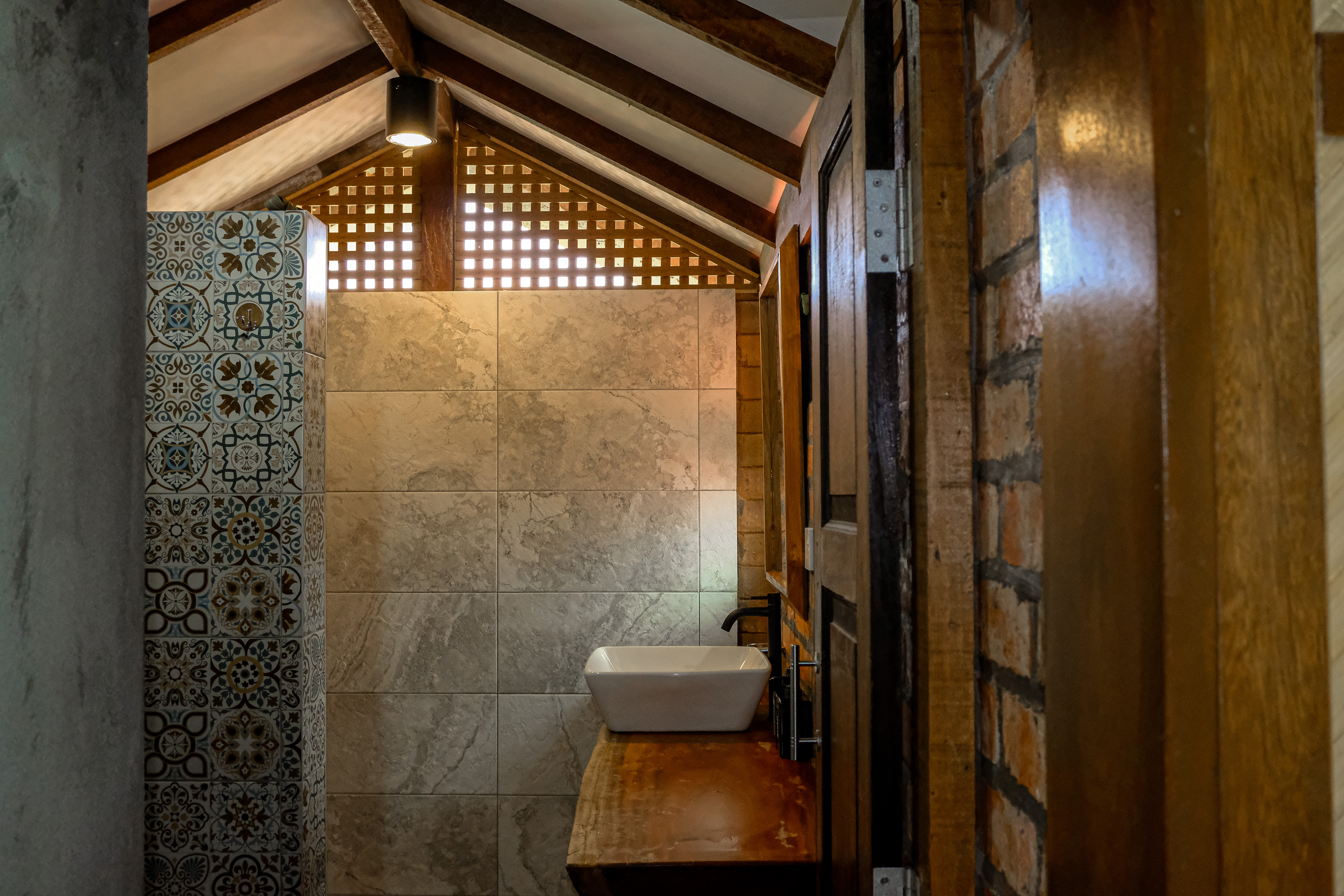 Bathroom detail with timber, patterned tiles and warm lighting at Villa Sawah